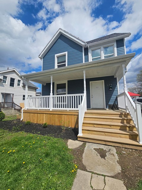 A blue house with a white porch and a wooden deck.