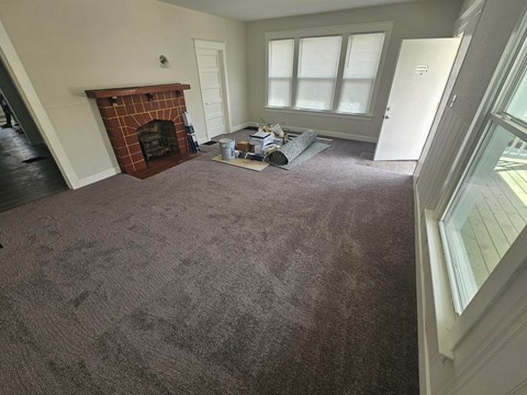 A room with a fireplace and carpet on the floor.