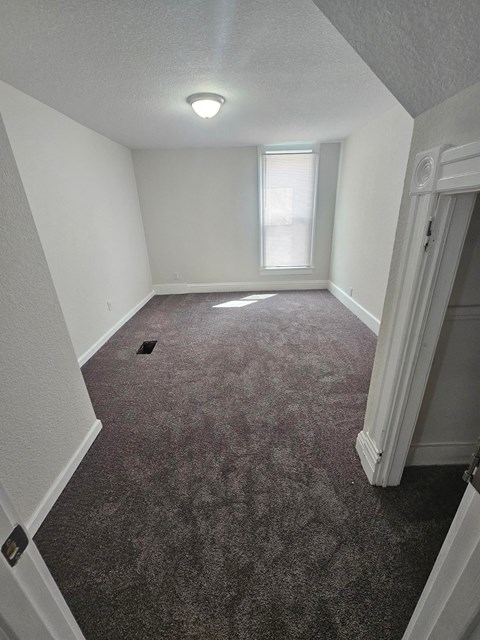 A room with a carpeted floor and a window.