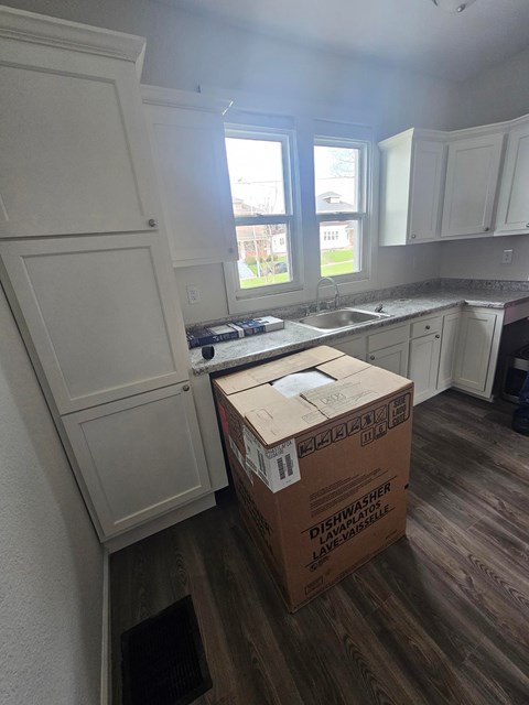 A kitchen with a box labeled Dishwasher on the floor.