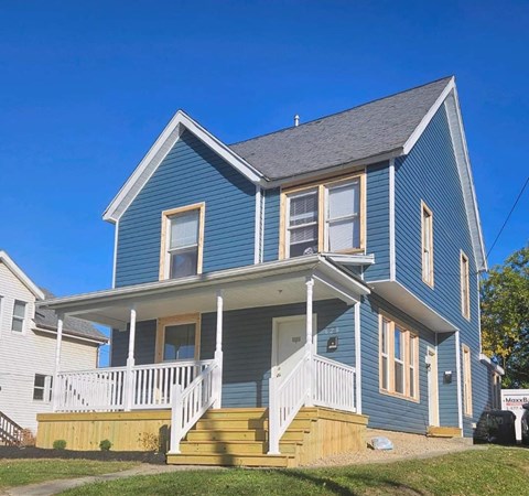 A blue house with white railings and a porch.