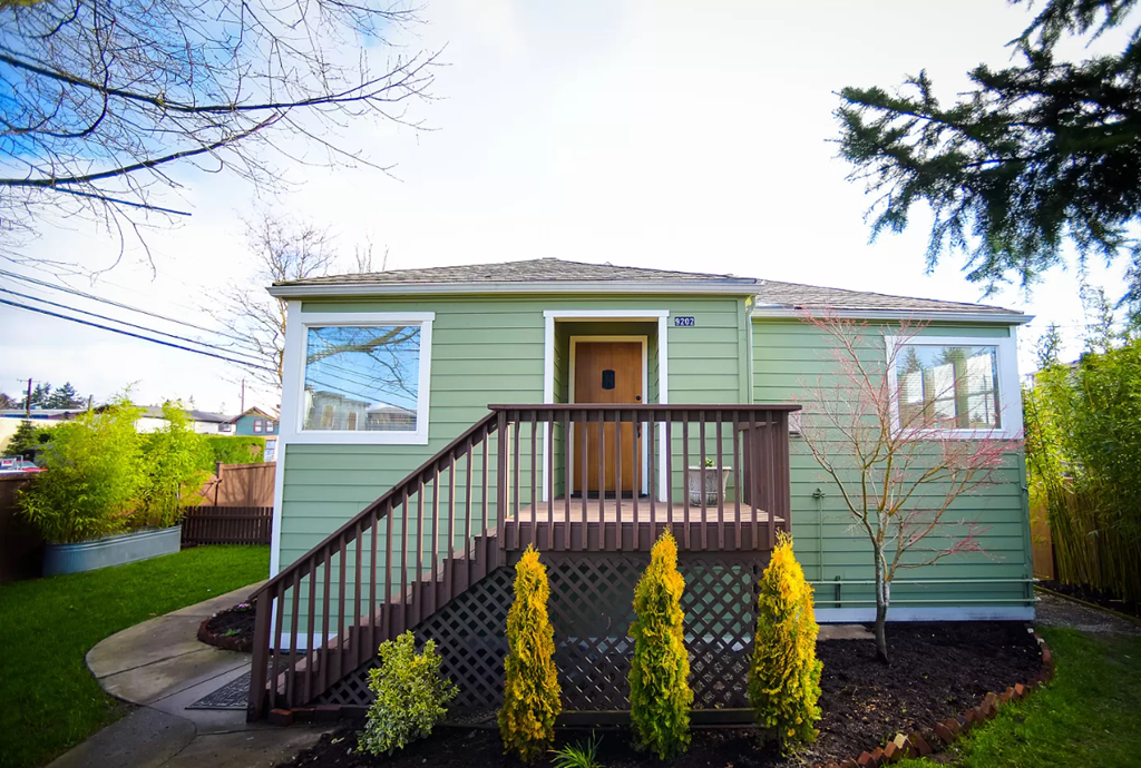 A green house with a brown door and a brown staircase.