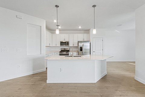 A kitchen with white cabinets and a white island with a microwave and oven on it.