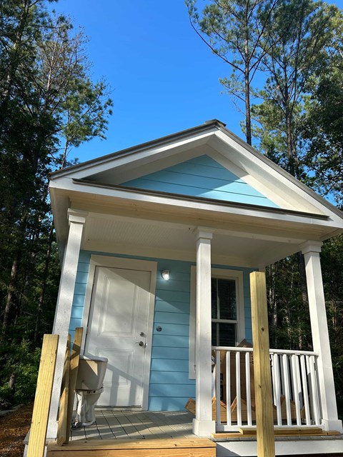 a small blue house with a white door and a porch