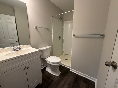 A white toilet sits in a bathroom next to a walk-in shower.