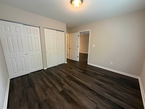 A room with two white doors and a wooden floor.