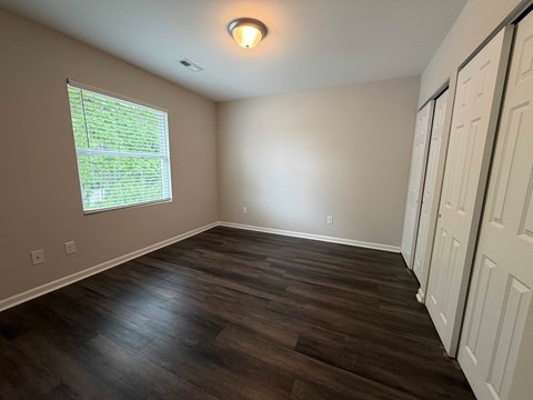 A room with a window and wooden flooring.