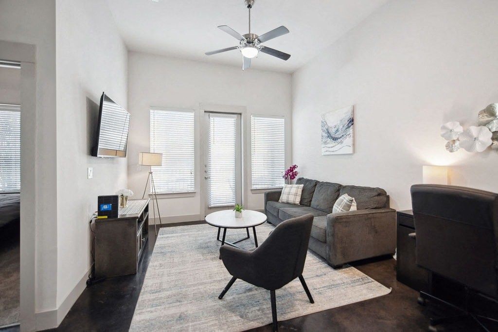 a living room with a couch and a chair and a ceiling fan
