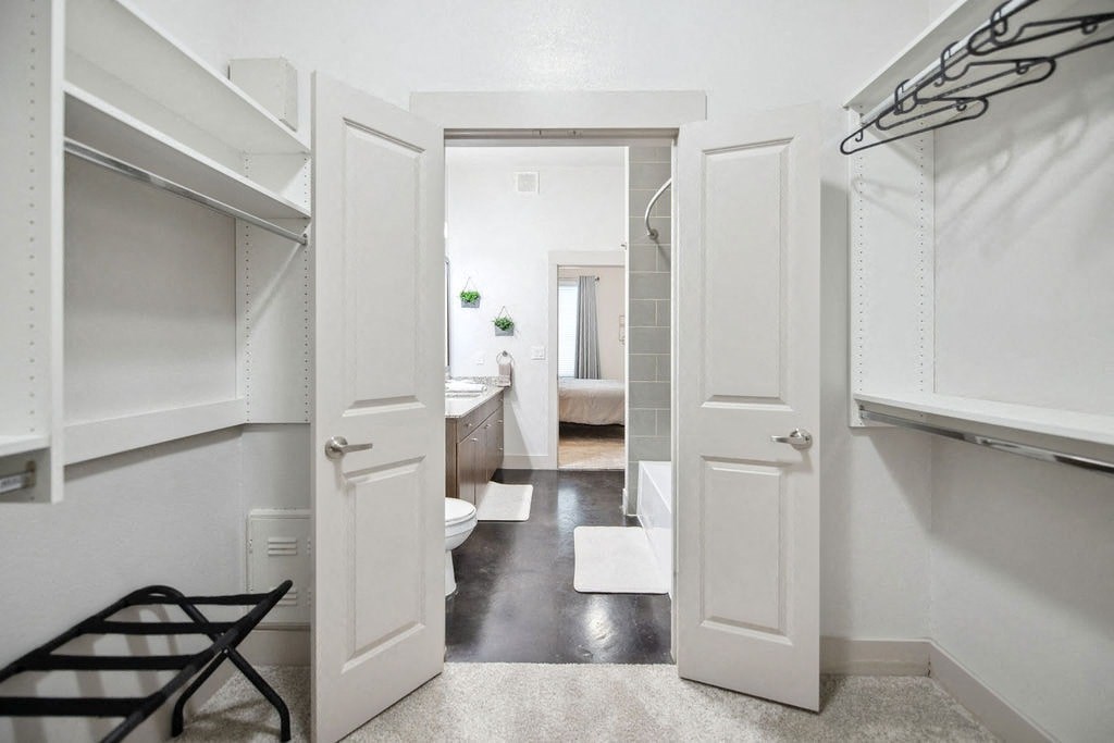 a white bathroom with white closets and a black chair