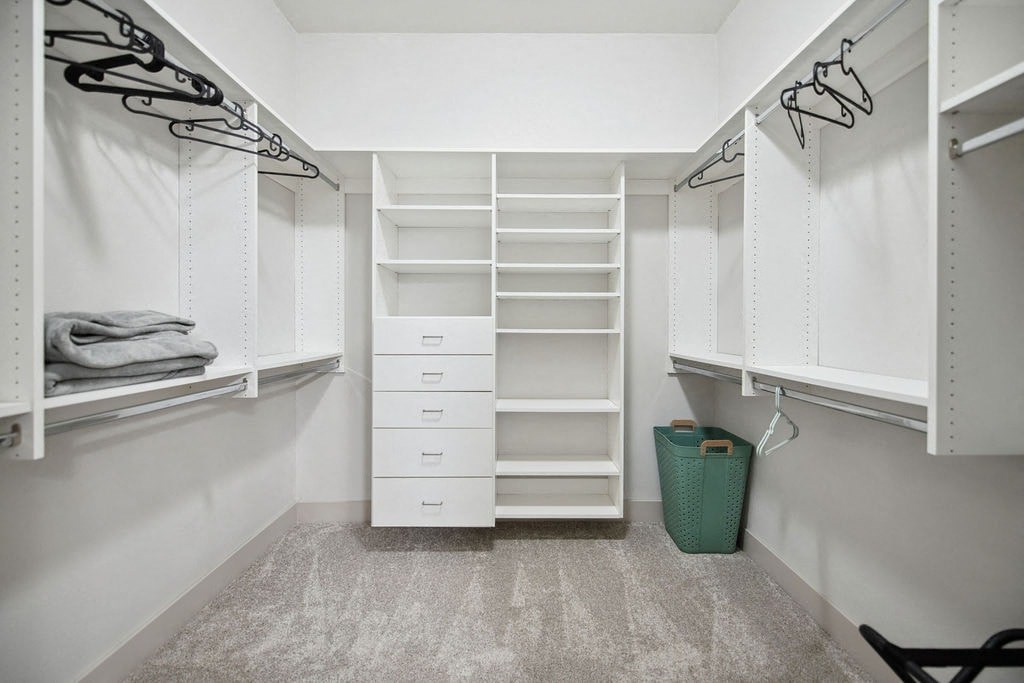 a large walk in closet with white shelves and drawers