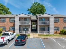 A parking lot in front of a two-story apartment building with cars parked.
