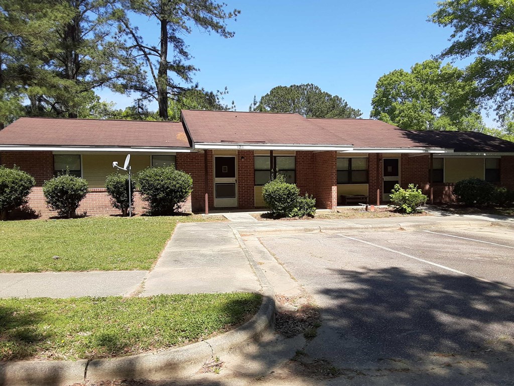 the front of a brick building with a parking lot