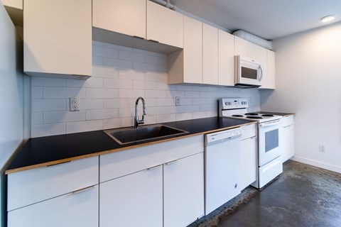 A kitchen with white cabinets and a black countertop.