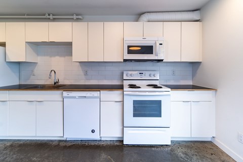A white kitchen with a stove, oven, and microwave.