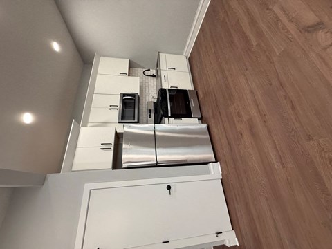 A kitchen with white cabinets and a microwave above the oven.