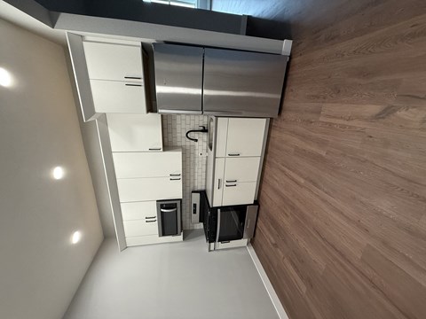A modern kitchen with wooden flooring and white cabinetry.