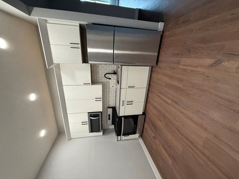 A modern kitchen with wooden flooring and white cabinets.