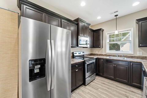 A modern kitchen with dark wood cabinets and stainless steel appliances.