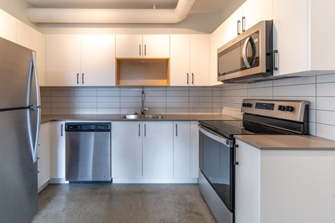 A modern kitchen with a refrigerator, oven, and microwave.