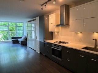 A modern kitchen with dark wood floors and white cabinets.