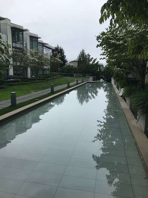 A long, narrow reflective pool in the middle of a grassy area.