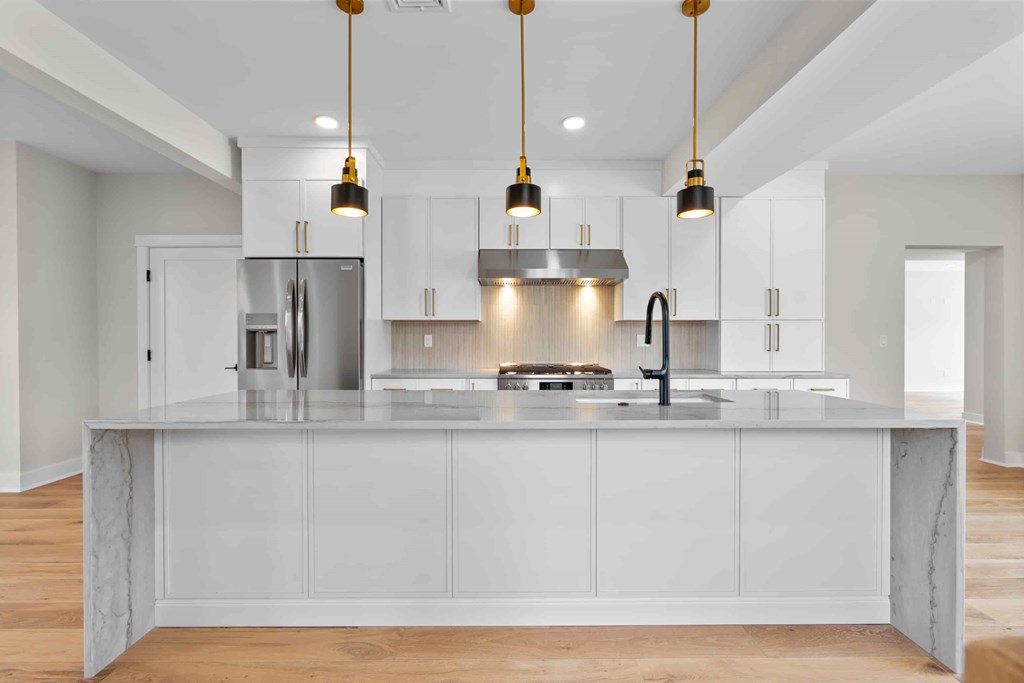 A modern kitchen with a marble island and pendant lights.