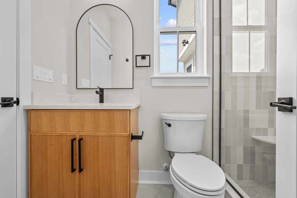 A white toilet sits next to a wooden cabinet in a bathroom.