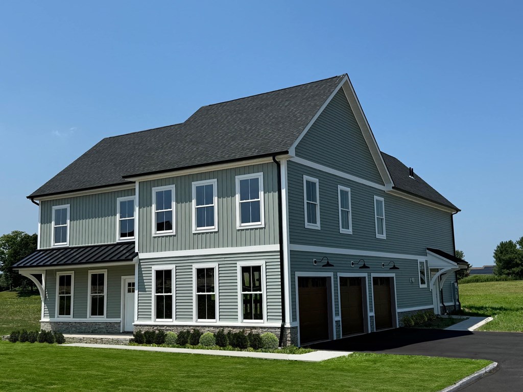 a large gray house with a gray roof and a lawn