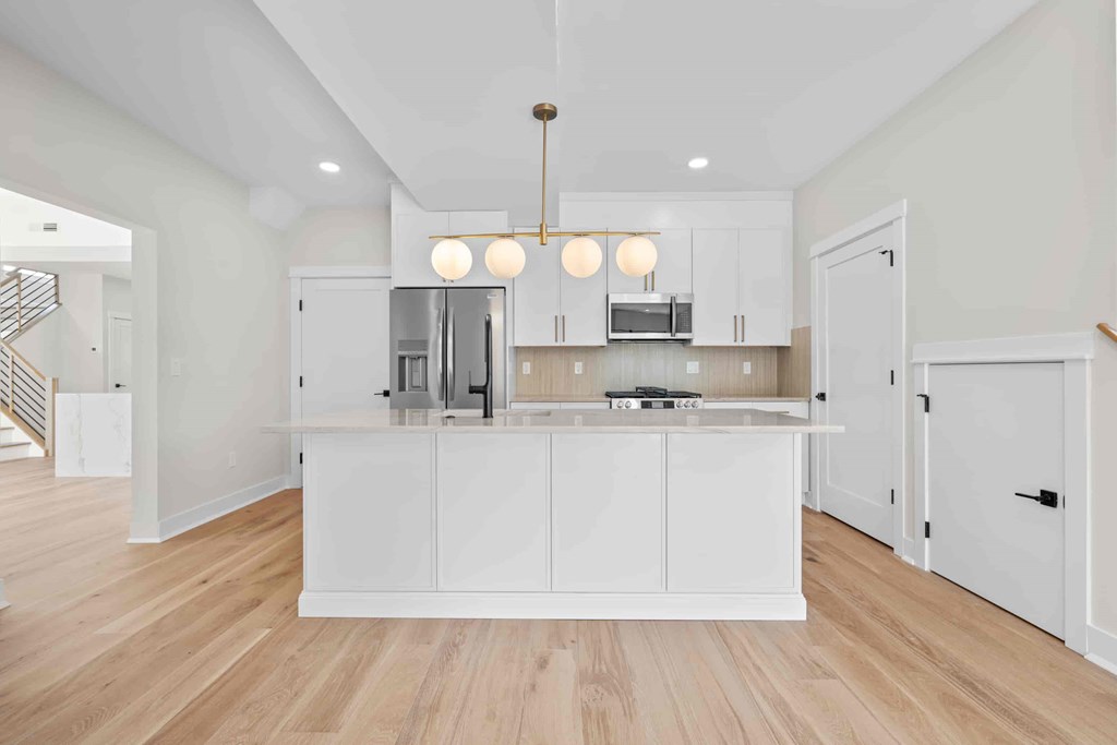 A kitchen with white cabinets and a wooden floor.