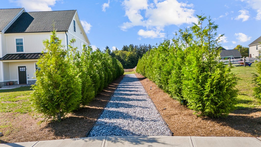 A white house with a black roof is surrounded by green trees.