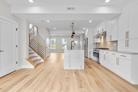 A modern kitchen with white cabinets and a wooden floor.