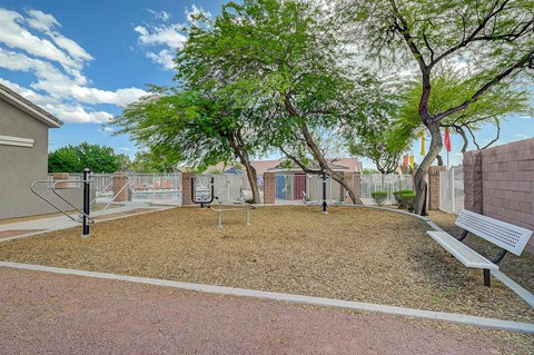 A park with a bench, a playground and a tree.