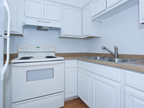 a kitchen with white cabinets and a stove and sink