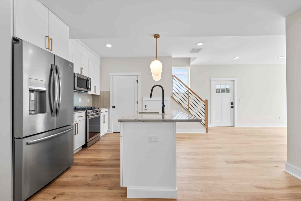 A modern kitchen with a wooden floor and stainless steel appliances.