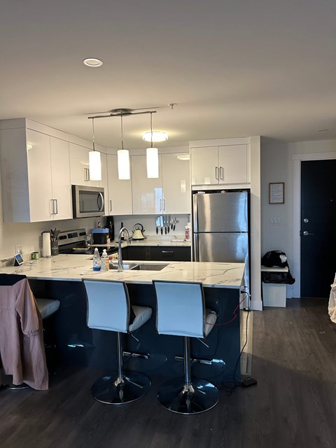 A kitchen with a white countertop and bar stools.