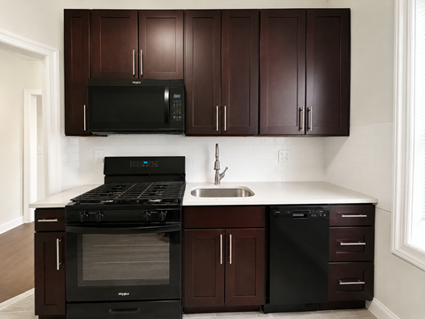 A kitchen with dark brown cabinets and black appliances.