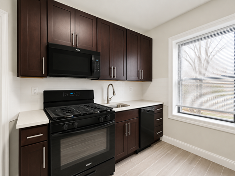 A kitchen with dark brown cabinets and black appliances.