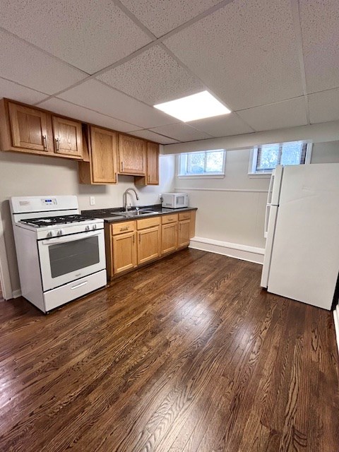 A kitchen with wooden floors and white appliances.