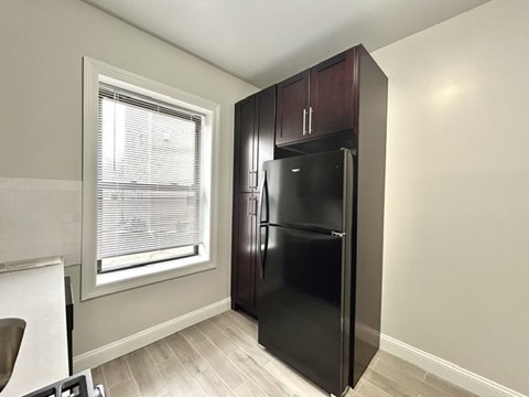 A black refrigerator in a kitchen with a window.