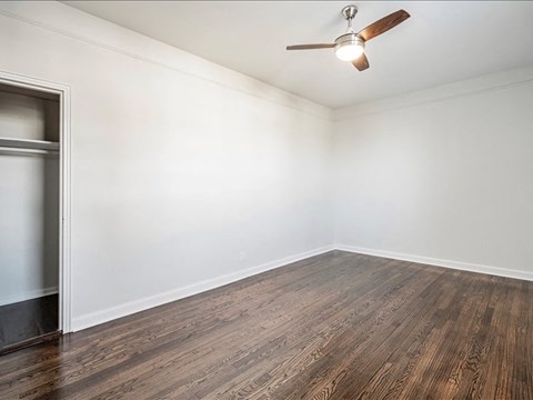 A room with a ceiling fan and wooden flooring.