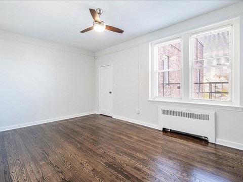 A room with a ceiling fan and a window with blinds.