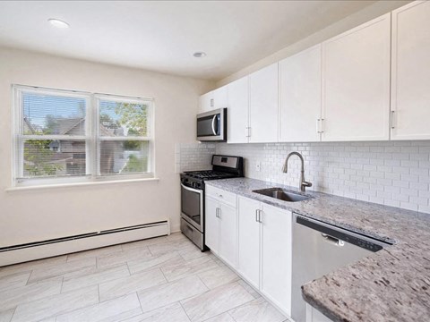 A kitchen with a granite countertop and white cabinets.