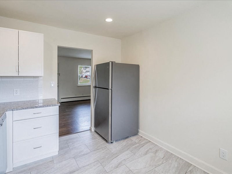 A kitchen with a refrigerator, countertop, and cabinets.