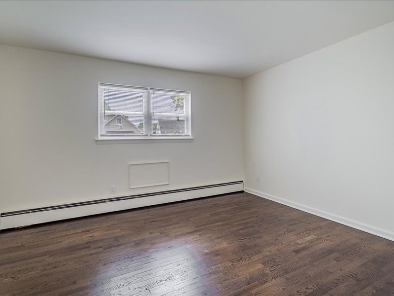 A room with a window and a wooden floor.