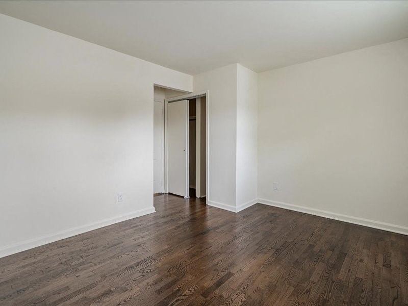 A room with a wooden floor and a white wall with a door.