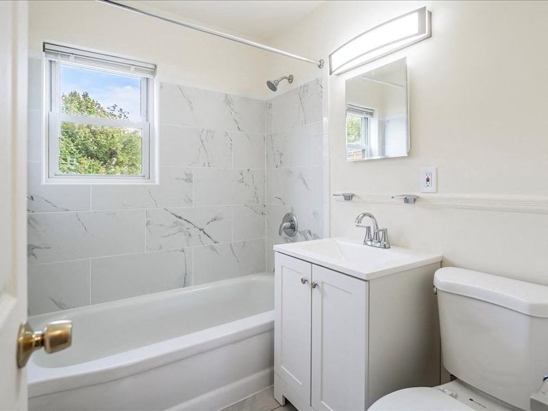 A white bathroom with a tub, sink, and toilet.