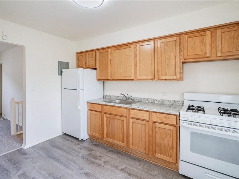 A kitchen with wooden cabinets and a white stove.