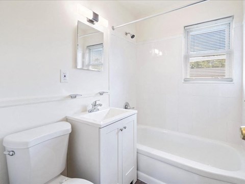 A white bathroom with a toilet, sink, and bathtub.