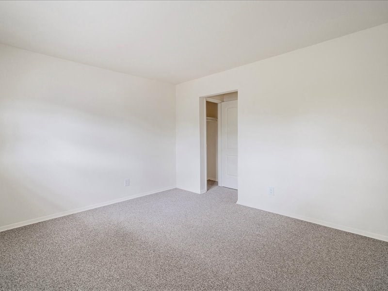 A room with a carpeted floor and a doorway leading to another room.