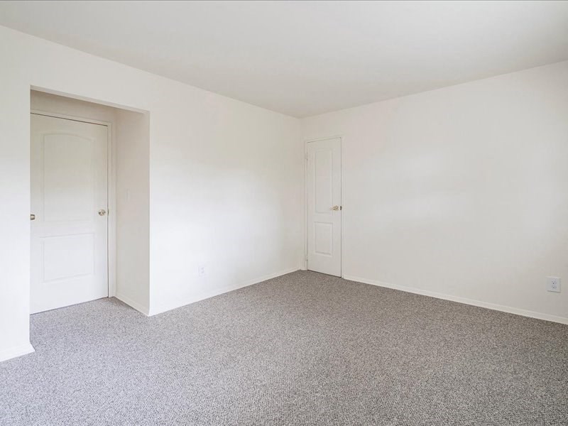 A room with carpeted floor and two doors.